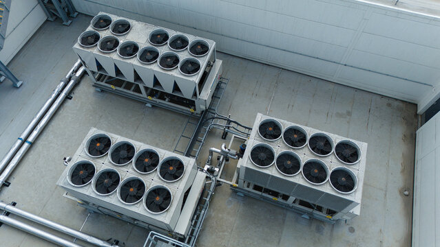 Aerial view of industrial ventilation cooling units, heat exchangers, and HVAC fans installed on a flat rooftop in Luton, England, United Kingdom.