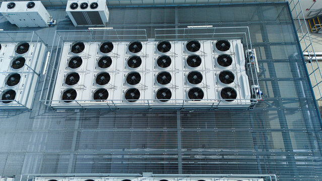 Aerial view of industrial ventilation cooling units, heat exchangers, and HVAC fans arranged in rows on a rooftop in Luton, England, United Kingdom.