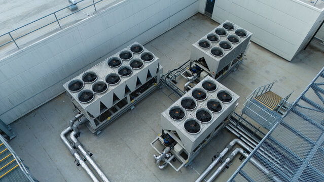 Aerial view of industrial ventilation cooling units, heat exchangers and HVAC fans installed on a flat rooftop in Luton, England, United Kingdom.