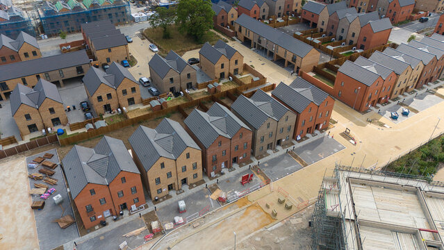 Aerial view of new residential housing construction featuring rows of modern brick houses with grey tiled roofs and paved driveways in a suburban development in Luton, England, United Kingdom.