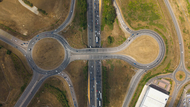 Aerial view of the M1 motorway junction 10 with its distinctive roundabout and surrounding logistics infrastructure in Luton, England, United Kingdom.
