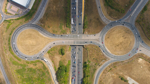 Aerial view of Junction Logistics at the M1 motorway junction 10 with traffic flowing through the roundabout and highway lanes Luton, England, United Kingdom.
