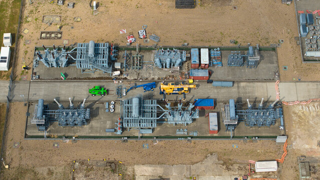 Aerial view of high voltage switchyard with electrical transformers, circuit breakers, and maintenance vehicles in Chalton, England, United Kingdom.