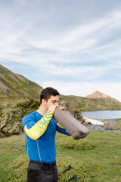 UGC Man inflating camping pillow beside alpine lake in Pyrenees