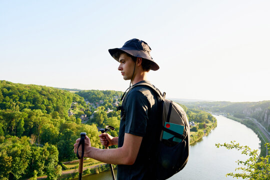 Hiker Standing on a Hillside Overlooking a River at Sunset