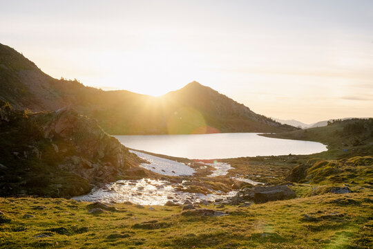 Sunset over alpine lake and mountain stream in Pyrenees