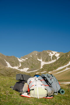Hiking backpacks below snowy peaks with blue sky in Pyrenees