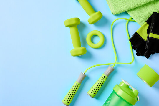 Green fitness equipment flat lay on blue background right side.