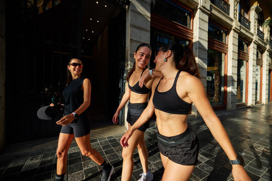 Three women walking on a city street during sunny afternoon