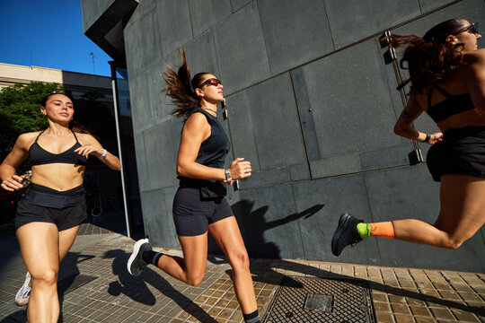Women run together on city street during daytime workout session