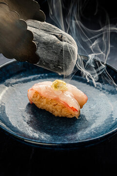 Aburi sushi nigiri being seared with hot charcoal by a chef