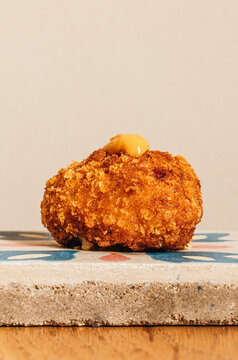 Close-up of a crispy gourmet Spanish croquette topped with sauce 