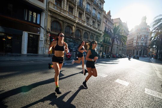 Women run on city street in the morning light during a fitness e