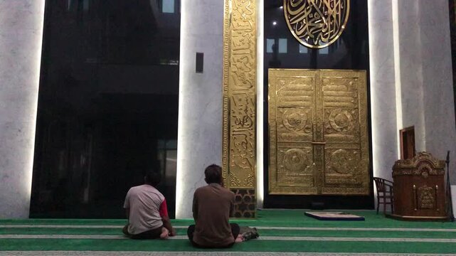 A Muslim worshipper praying inside a mosque during a religious observance. The individual is seen performing prayer inside the mosque