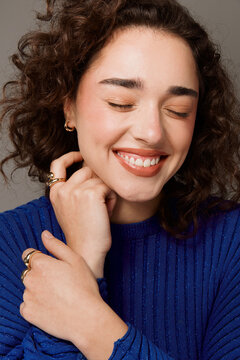 Portrait of a young woman smiling, wearing a blue sweater