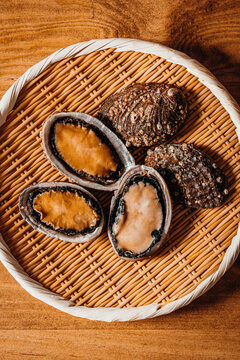 Raw fresh abalone displayed in a traditional woven bamboo basket