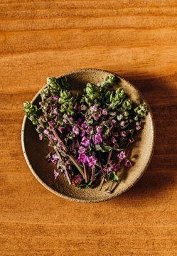 Overhead view of fresh purple shiso flowers in a small ceramic bowl