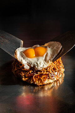 Placing a double-yolk fried egg on top of yakisoba noodles
