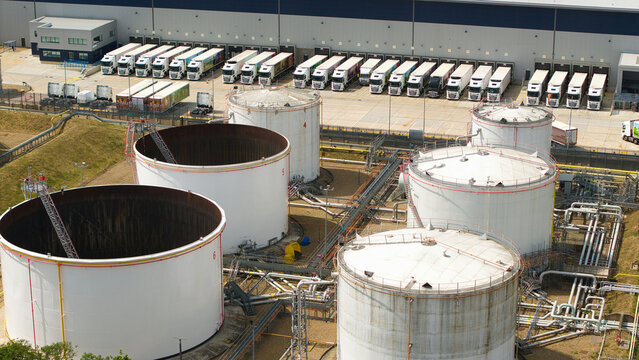 Aerial view of Buncefield Oil Depot featuring large white storage tanks, complex piping infrastructure, and numerous HGVs parked at loading bays in Hemel Hempstead, England, United Kingdom.
