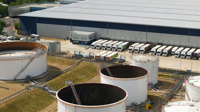 Aerial view of Buncefield Oil Depot and distribution centre with white storage tanks and rows of HGVs parked at warehouse loading bays in Hemel Hempstead, England, United Kingdom.