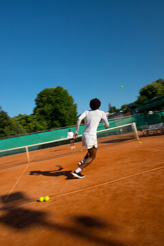 Black man tennis player blurred into motion with racket and ball.