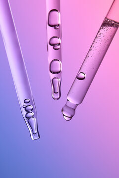 Glass pipettes with liquid on gradient pink and purple background.