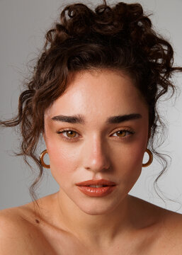 Model With Curly Hair and Hoop Earrings Poses With a Serious Look