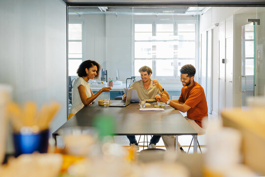 Workmates collaborating during lunch break in modern workspace