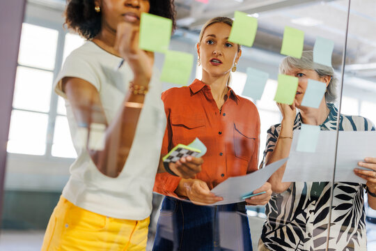 Women doing brainstorming ideas on glass wall