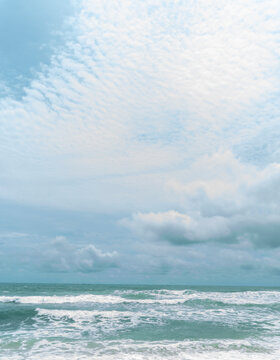 Beautiful ocean waves rolling under bright blue cloudy sky on tropical beach landscape