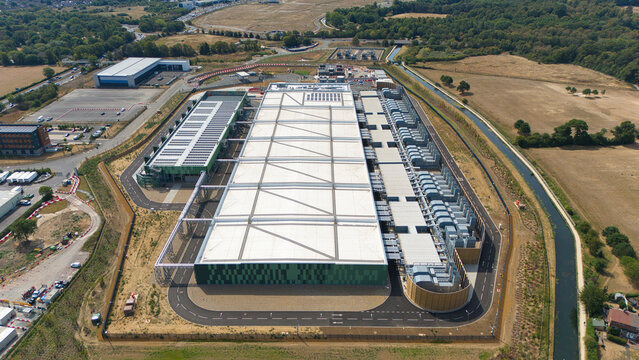 Aerial view of a hyperscale data center featuring large white rooftops, rows of air handling units, and industrial chillers in Hereford, England, United Kingdom.