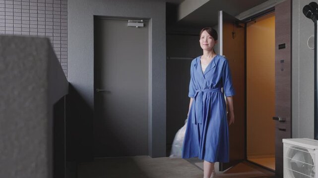 マンションからゴミ出しに向かう女性
