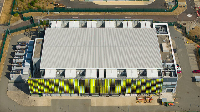 Aerial view of a modern data center facility featuring containerised diesel generators and cooling systems for AI infrastructure in Harlow, England, United Kingdom.