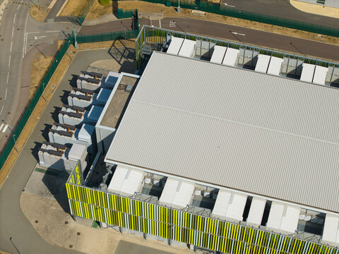 Aerial view of a data center facility featuring rows of containerised diesel generators and cooling units for AI infrastructure in Harlow, England, United Kingdom.