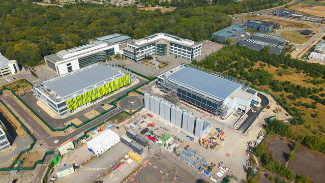 Aerial view of a modern data center complex featuring containerised diesel generators and cooling infrastructure for AI operations in Harlow, England, United Kingdom.