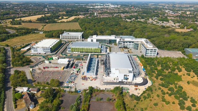 Aerial view of a modern data center facility featuring containerised diesel generators and cooling systems for AI infrastructure, located in Harlow, England, United Kingdom.