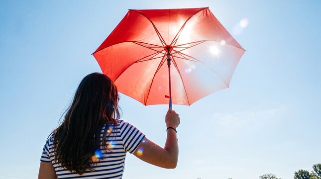 Woman Holding Red Umbrella Against Sunny Blue Sky, Rear View