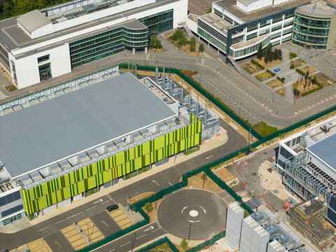 Aerial view of a modern data center facility featuring containerized diesel generators and cooling systems for AI infrastructure, situated in Harlow, England, United Kingdom.