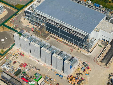 Aerial view of a modern data center facility featuring rows of containerised diesel generators and advanced cooling systems for AI infrastructure in Harlow, England, United Kingdom.