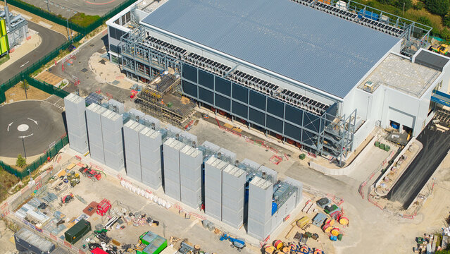 Aerial view of a modern data center featuring rows of containerised diesel generators and large-scale cooling infrastructure for AI operations in Harlow, England, United Kingdom.
