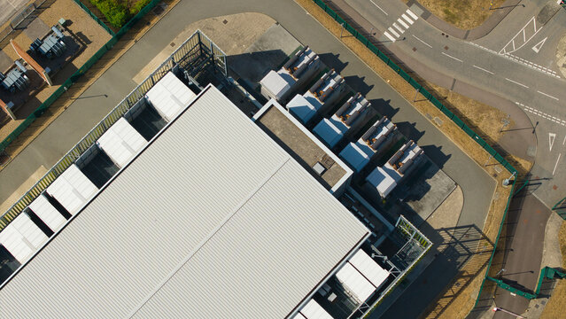 Aerial view of a data center facility featuring containerised diesel generators and cooling units for AI infrastructure in Harlow, England, United Kingdom.