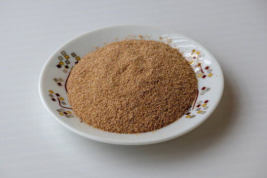 Heap of raw wheat bran flakes in small plate on white background. Natural cereal husk ingredient, dietary fiber nutrition, and organic food concept.
