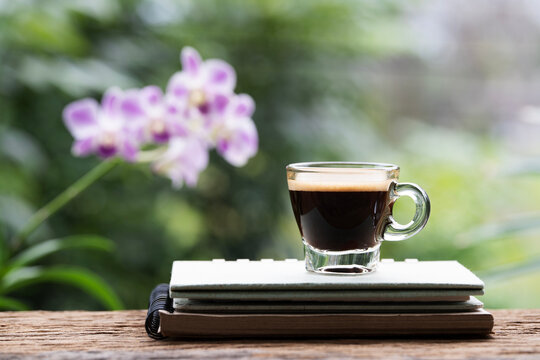 Macro closeup of coffee glass cup on stack of notebooks