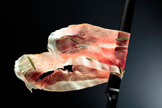 Sliced prosciutto on a kitchen knife.