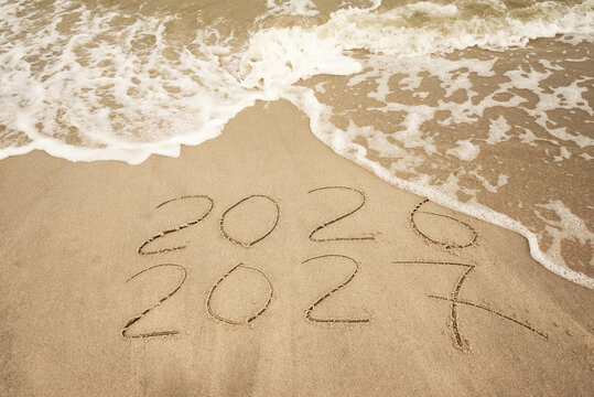 Inscription 2026 and 2027 numbers written on sand.  New Year 2026 replace 2027. Concept on the sea beach