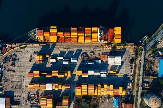 Aerial view of Batumi International Container Terminal with colorful shipping containers stacked on the dock and a cargo ship moored at the pier in Batumi, Adjara, Georgia.