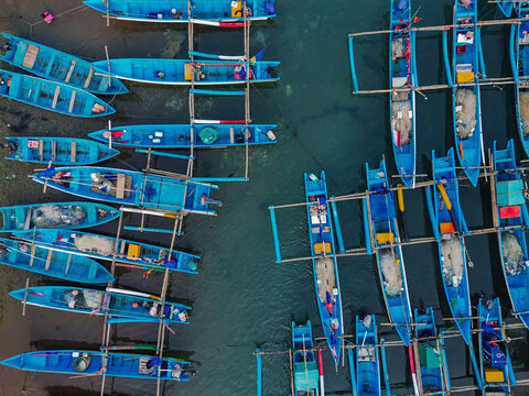 Aerial view of traditional blue fishing boats moored in the clear waters of Baron Beach in Yogyakarta, Special Region of Yogyakarta, Indonesia.