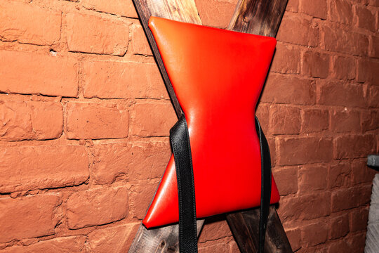 Red cushioned restraint leans against rustic brick wall