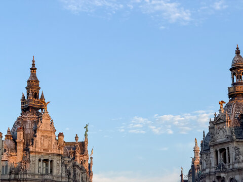 Ornate historic building domes and spires against a soft blue sky at golden hour in Antwerpen, Belgi&euml;