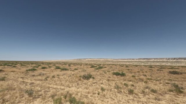 SUV driving through expansive dry landscape with distant hills and clear sky